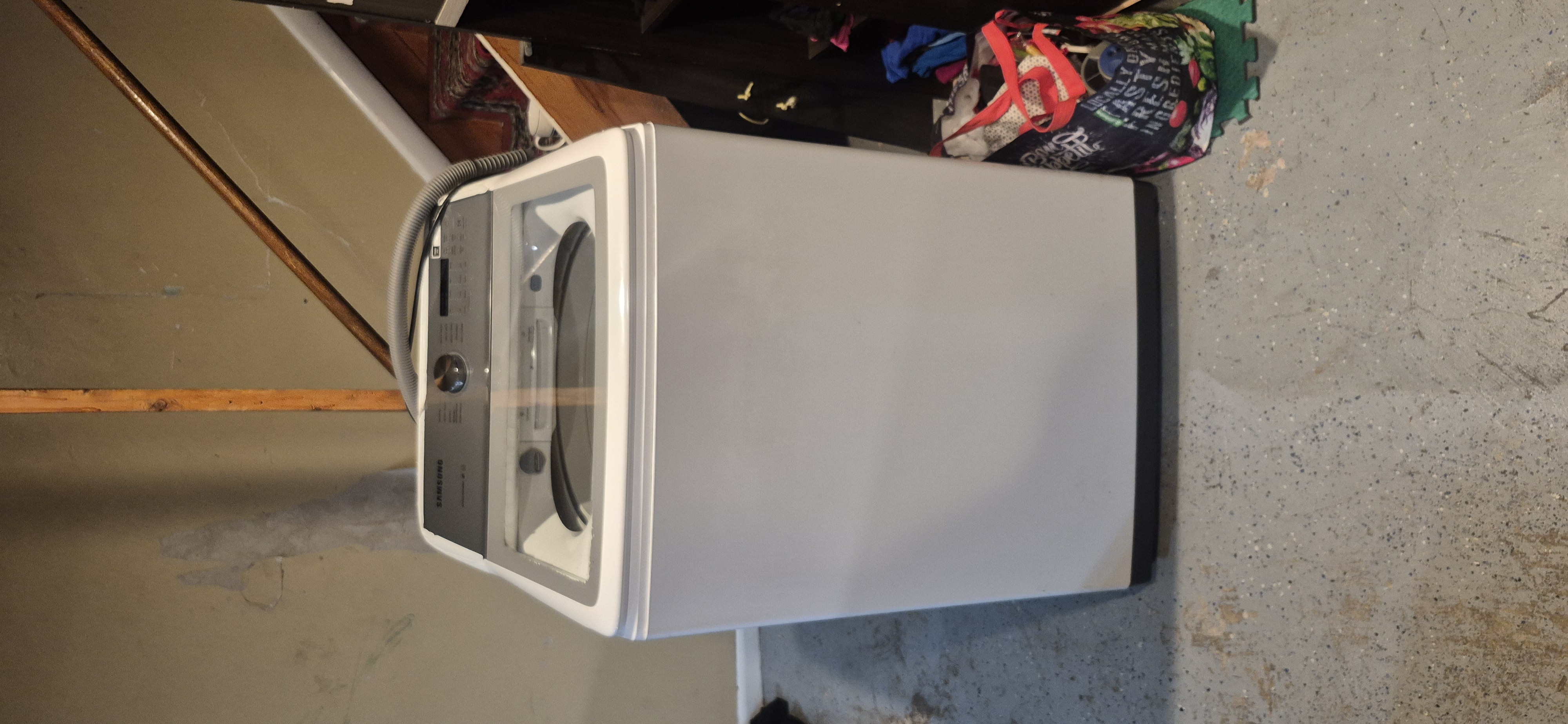 Samsung top-load washing machine ready for appliance removal from a basement