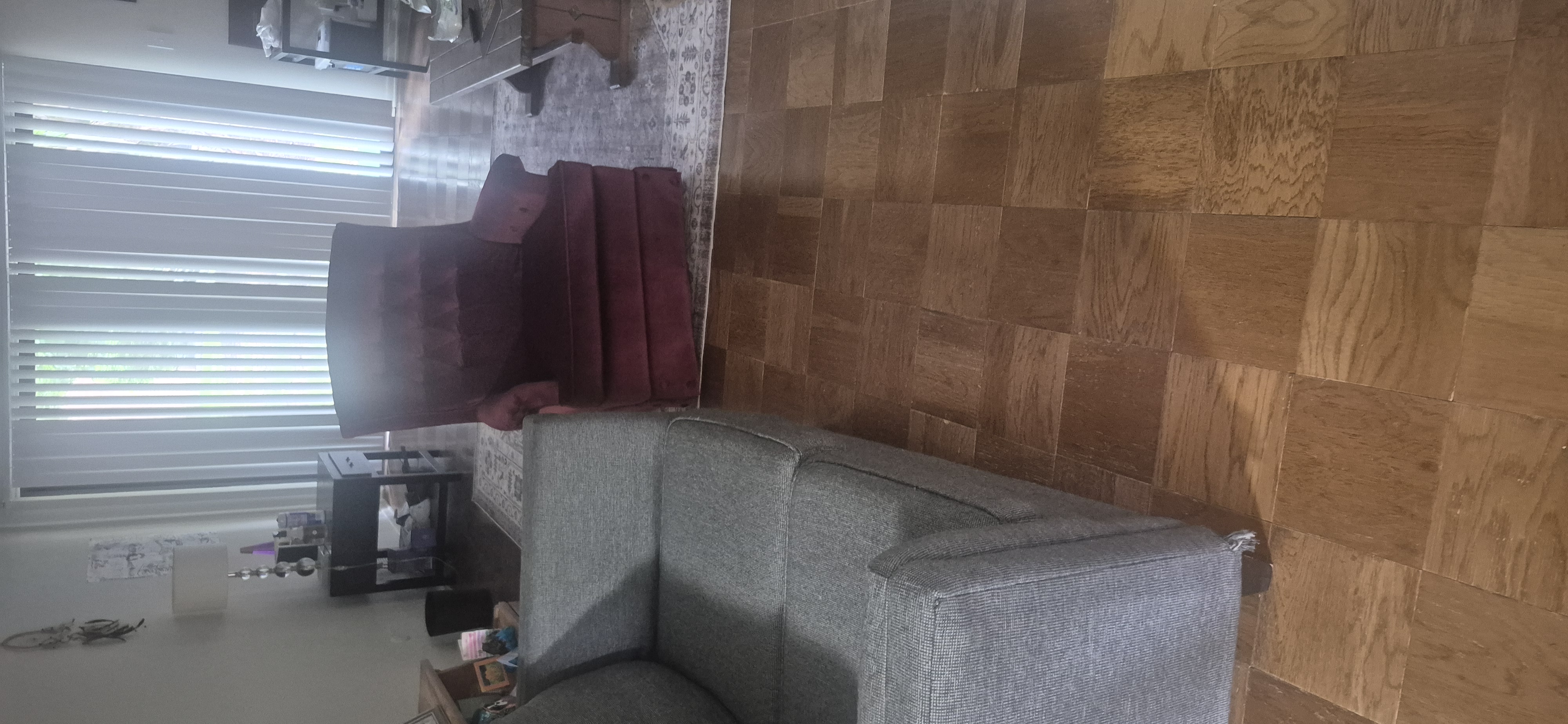Living room with a gray sofa and maroon recliner scheduled for furniture removal