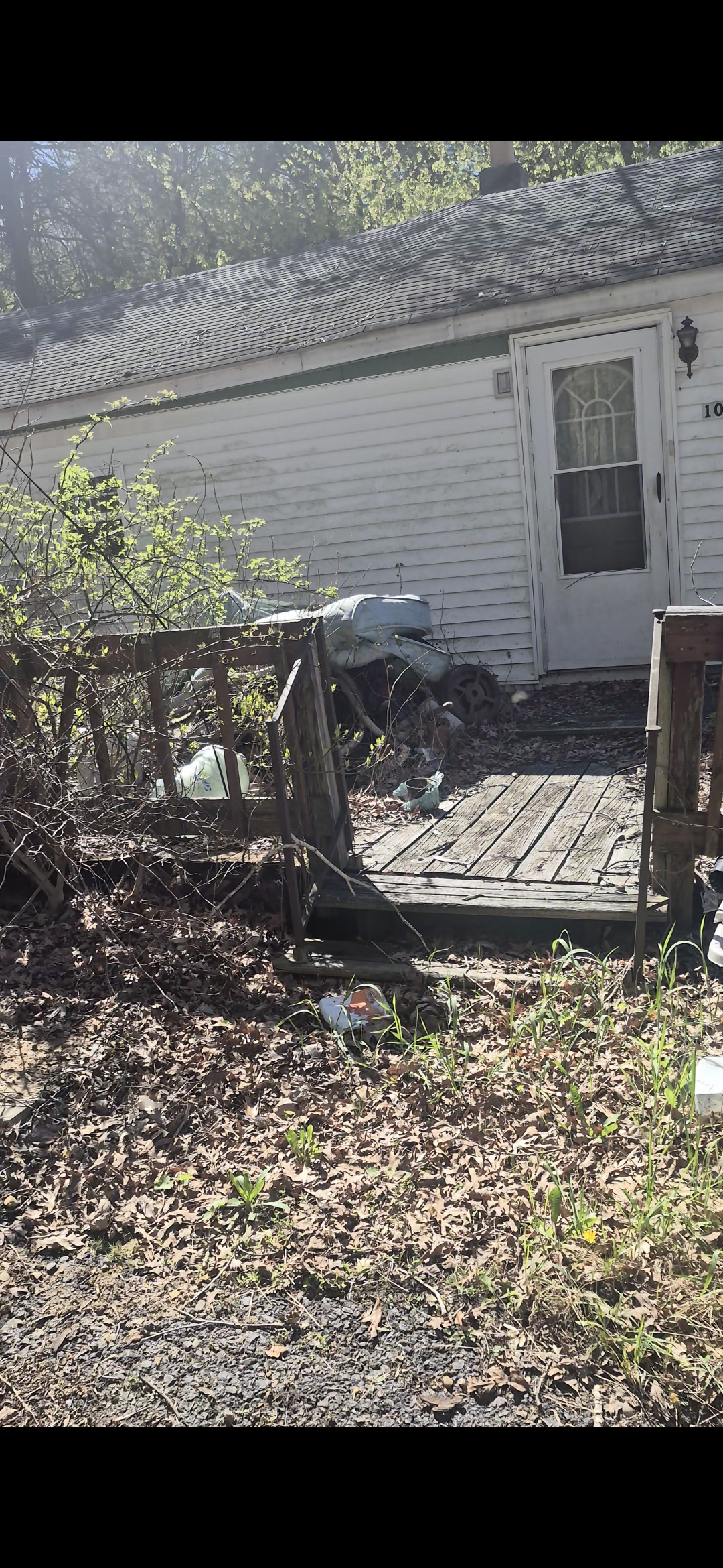 Rundown house with a rotting wood deck slated for light demolition and removal